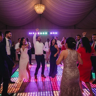 Wedding guests dancing excitedly on a dance floor with colorful lights